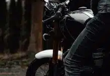 person in black jacket and blue denim jeans riding on motorcycle