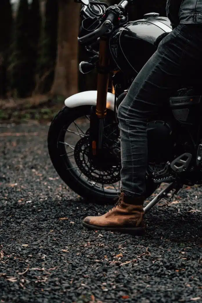 person in black jacket and blue denim jeans riding on motorcycle