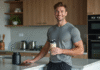 Prendre du muscle : quelle whey choisir pour optimiser sa croissance musculaire ? Jeune homme sportif avec shaker de proteine dans la cuisine