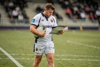 Joueur de rugby consultant le calendrier de la Nationale 2026 au bord du terrain
