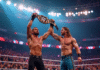 Deux lutteurs WWE dans un stade rempli avec un champion haut